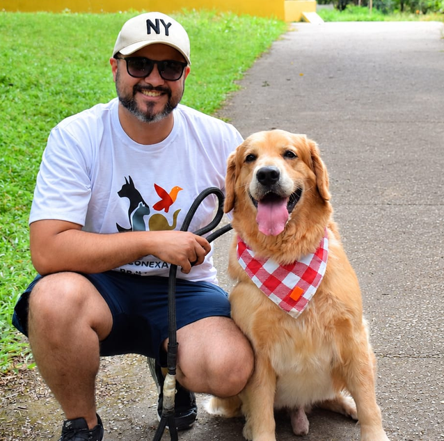 Homem com camiseta da Conexão Protetora ao lado de um golden retriever